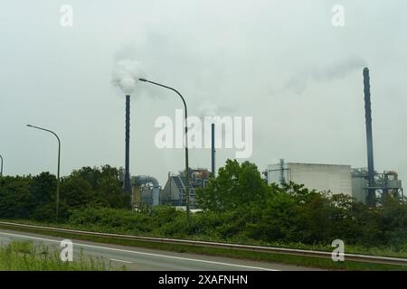 Eine Fabrik, die Rauch aus ihren hohen Stapeln in den Himmel bläst, zeigt industrielle Aktivität und Verschmutzung. Stockfoto