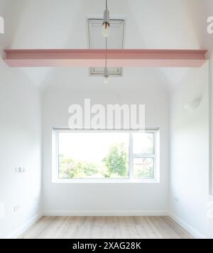 Edwardian House in London: Architekt entwarf minimalistischen Wohnraum mit gewölbtem Dach und freiliegendem Balken in Pink. Das Zimmer ist weiß gestrichen. Stockfoto