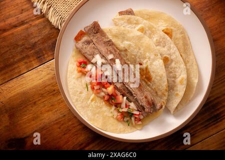 Arrachera Tacos. Mariniertes Rindersteak serviert in einer Weizentortilla auf einer mexikanischen Tonplatte. Street Food aus Mexiko, traditionell begleitet von Cila Stockfoto