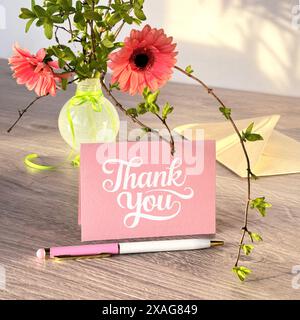 Pinke Dankeskarte mit Blumenvase und Stift auf Holztisch Stockfoto