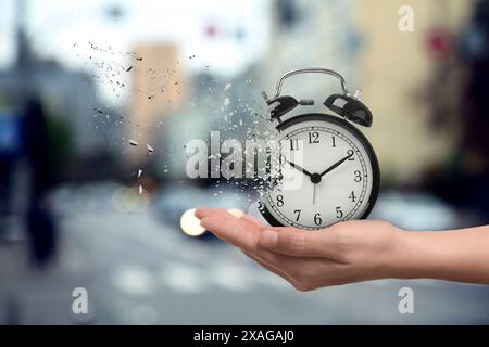 Die Zeit wird knapp. Frau mit auflösendem Wecker auf verschwommenem Hintergrund, Nahaufnahme Stockfoto