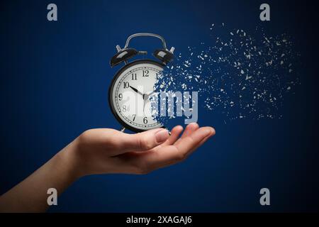 Die Zeit wird knapp. Frau mit auflösendem Wecker auf blauem Hintergrund, Nahaufnahme Stockfoto