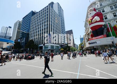 Fußgänger überqueren die Queens Street entlang der Victoria Street in Auckland, Neuseeland. Stockfoto