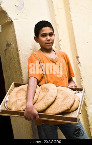 Ein marokkanischer Junge mit traditionellem marokkanischem Pita-Brot aus einer Bäckerei in Fes, Marokko. Stockfoto