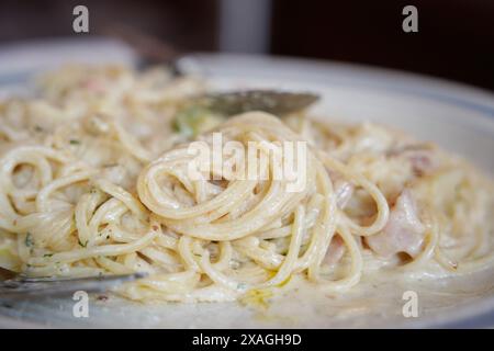 Spaghetti Carbonara mit Schinken und Käse auf weißem Teller auf dem Tisch Stockfoto