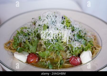 Basilikum-Spaghetti mit Pesto-Sauce und frischem Gemüse auf weißem Teller Stockfoto