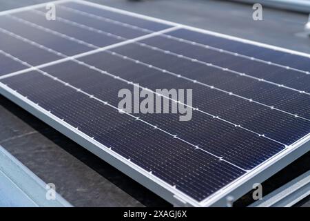 Photosolarpaneele werden auf einem flachen gewerblichen, industriellen EPDM-Dach mit Betonballastblöcken installiert. Stockfoto