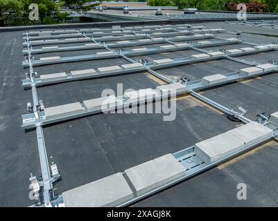 Foto von Rahmen- und Betonblockballasthöcken für neue Solarpaneele, die auf einem flachen gewerblichen, industriellen EPDM-Dach installiert werden. Stockfoto