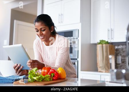 Tablette, Gemüse und Frau in der Küche mit Rezept für Gesundheit, Wellness und Diät Mahlzeit. Kochen, Zutaten und indische weibliche Person mit Digital Stockfoto