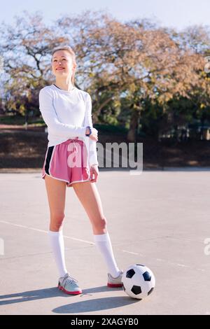 Frau neben einem Fußball, bereit zum Fußball Stockfoto