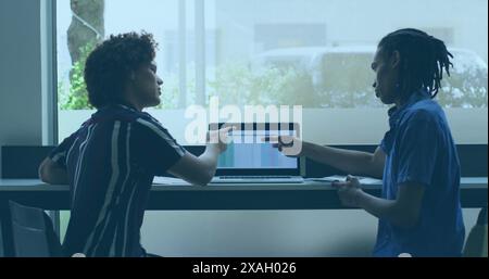Zwei junge Männer diskutieren etwas auf dem Laptop-Bildschirm in einem modernen Büro Stockfoto