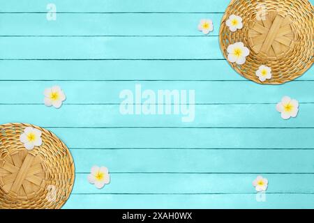 Strohbraune Hüte mit Plumeria-Blüten auf blauen Holzbrettern. Urlaub, Reisen, Tourismus in heißen tropischen Ländern. Kopierbereich Stockfoto