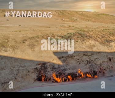 Ein Blick auf den brennenden Berg Yanar Dag in Baku, Aserbaidschan, mit Flammen, die aus dem Boden auftauchen. Das Schild Yanar Dag ist im Hintergrund sichtbar Stockfoto