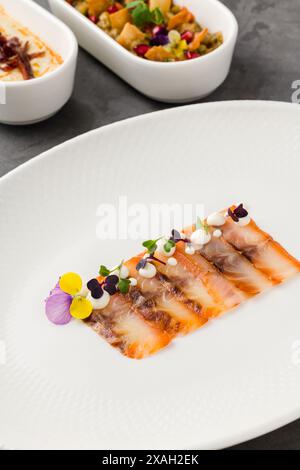 Geräucherter Fisch, Pastrami oder Speck auf einem weißen Porzellanteller Stockfoto