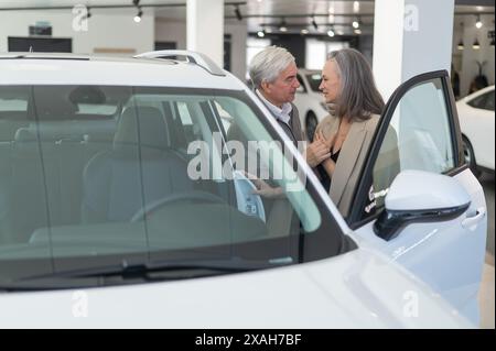 Ein älteres kaukasisches Paar wählt ein neues Auto in einem Autohändler. Stockfoto