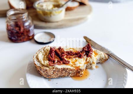 Stück Brot mit Hummus und sonnengetrockneten Tomaten auf einem weißen Teller. Hochwertige Fotos Stockfoto