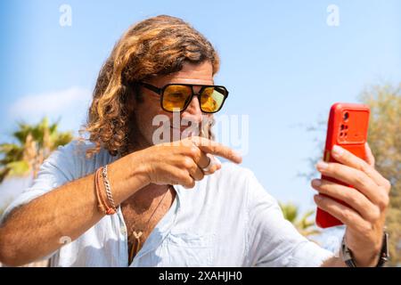 Lächelnder Mann im Strandurlaub, der mit einem Freund über Videoanrufe spricht. Stockfoto