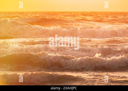 Sonnenuntergang über dem Meer. Riplpe Meerwasseroberfläche mit kleinen Wellen. Seewasserschaumspritzer. Wunderschöne Naturlandschaft Stockfoto