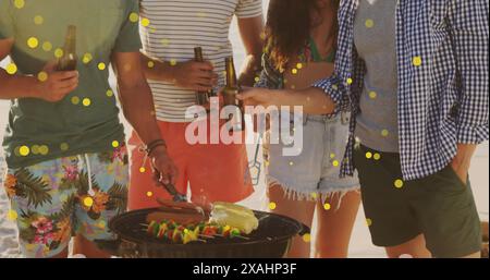 Bild von gelben Flecken über verschiedenen Gruppen von Freunden, die Bier trinken und am Strand grillen Stockfoto