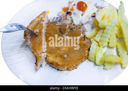 Gestanztes gegrilltes Rindfleischsteak mit frittiertem französisch auf weißem Teller auf weißem isoliert. Stockfoto