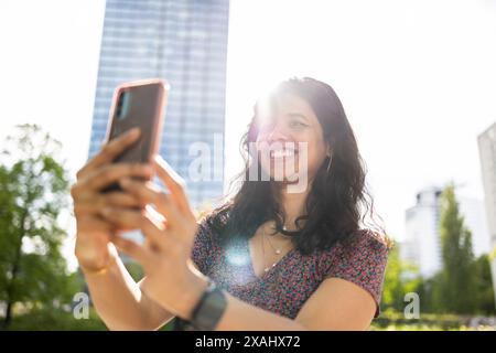 Lächelnde junge Frau, die ihr Smartphone in der Stadt benutzt Stockfoto