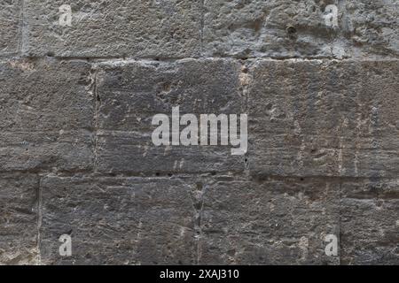 Flache Nahaufnahme einer alten grauen Steinmaueroberfläche, hintergrundstrukturierter Hintergrund Stockfoto