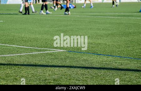 Fußballfeld, im Hintergrund unscharf mit einem Spieler, der auf dem Boden zwischen den Beinen anderer Spieler liegt. Stockfoto