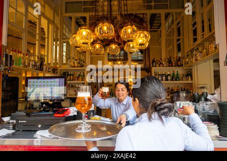 Palma, Balearen, Spanien, Kellnerin, die eine Tasse Bier vom Fass von einem Barkeeper bekommt, nur Redaktion. Stockfoto