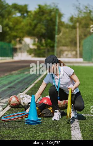 Weibliche Trainerin, die sich auf das Outdoor-Fußballtraining für Kinder vorbereitet. Einrichtung der erforderlichen Ausrüstung für Training und Aufwärmen. Stockfoto