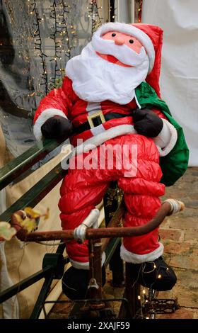 Der Weihnachtsmann fährt auf einem rostigen Fahrrad, während er Geschenke überbringt. Straßendekoration. Frankreich. Stockfoto