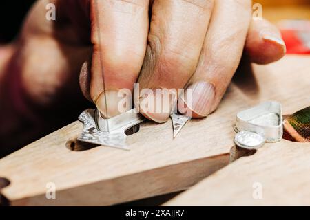 Nahaufnahme von Juwelierhändern, die mit Juweliersägen arbeiten Stockfoto