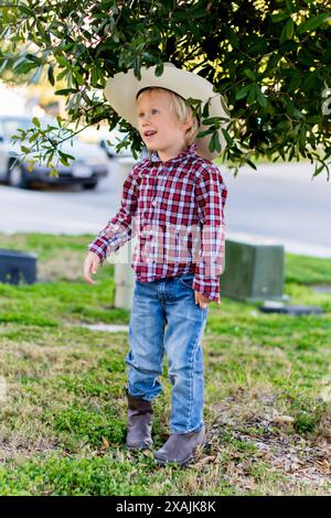 Junger Cowboy in westlicher Kleidung, der an einem Baum steht Stockfoto