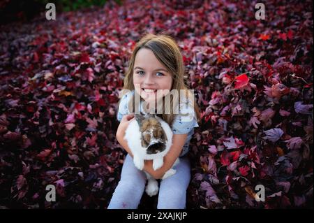 Glückliches kleines Mädchen, das Holland Lop Hase draußen hält Stockfoto