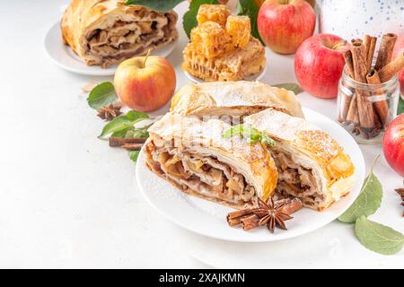 Hausgemachter herbstlicher Apfelstrudel mit karamelisierten Äpfeln, Rosinen, Nüssen, Honig, Zimtgewürzen, auf Teller auf Küchentisch Kopierraum Stockfoto