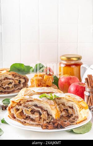 Hausgemachter herbstlicher Apfelstrudel mit karamelisierten Äpfeln, Rosinen, Nüssen, Honig, Zimtgewürzen, auf Teller auf Küchentisch Kopierraum Stockfoto