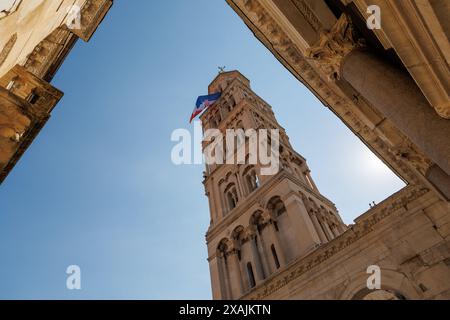 Eine kroatische Flagge fliegt gegen den blauen Himmel, während Sie den Turm vom Hof des Diokletian-Palastes in der Altstadt von Spli aus betrachten Stockfoto