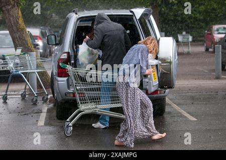 Charlotte Church und ihre Kinder Ruby und Dexter bilden zusammen mit ihrem Freund Jonathan Powell die perfekte Familiengruppe, wenn sie heute in einem Supermarkt in der Nähe ihres Hauses außerhalb von Cardiff einkaufen gehen. Aber was für ein Unterschied ein paar Stunden machen... Sie kamen bei warmem Sonnenschein an und gingen in einem sintflutartigen Regenguss zurück. Stockfoto