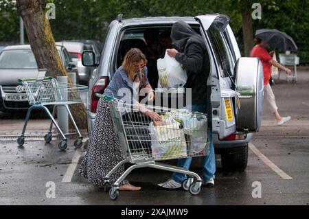 Charlotte Church und ihre Kinder Ruby und Dexter bilden zusammen mit ihrem Freund Jonathan Powell die perfekte Familiengruppe, wenn sie heute in einem Supermarkt in der Nähe ihres Hauses außerhalb von Cardiff einkaufen gehen. Aber was für ein Unterschied ein paar Stunden machen... Sie kamen bei warmem Sonnenschein an und gingen in einem sintflutartigen Regenguss zurück. Stockfoto