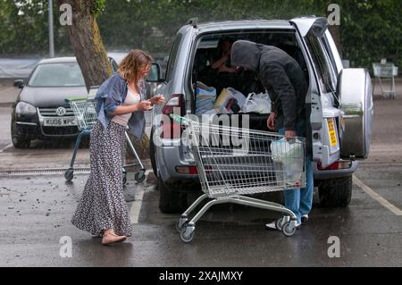Charlotte Church und ihre Kinder Ruby und Dexter bilden zusammen mit ihrem Freund Jonathan Powell die perfekte Familiengruppe, wenn sie heute in einem Supermarkt in der Nähe ihres Hauses außerhalb von Cardiff einkaufen gehen. Aber was für ein Unterschied ein paar Stunden machen... Sie kamen bei warmem Sonnenschein an und gingen in einem sintflutartigen Regenguss zurück. Stockfoto
