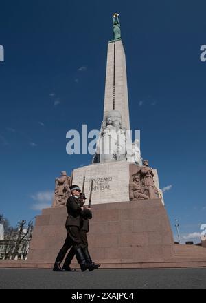 Zwei Soldaten marschieren vor dem Freiheitsdenkmal in Riga. Das Denkmal wurde 1935 geweiht und trägt die Inschrift „für Vaterland und Freiheit“ in Riga, Lettland Stockfoto