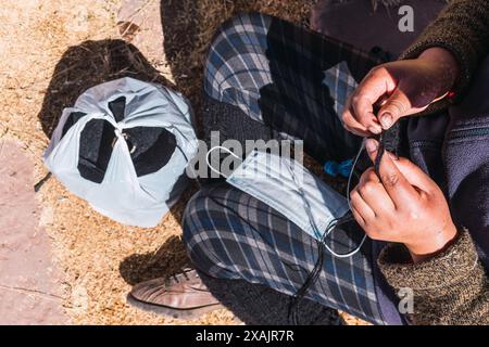 Hände einer Andenfrau, die braune Alpakafasern in einem angestammten Spinnrad im Andengebirge in einer Handwerkstatt spinnen Stockfoto