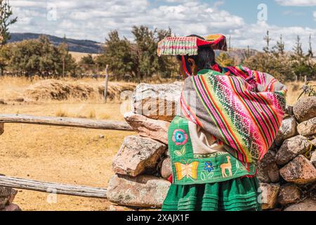 Einheimische Frauen wandern in typischen Kostümen aus Alpakasfasern an einem sonnigen Tag mit blauem Himmel und Wolken in den Anden Stockfoto