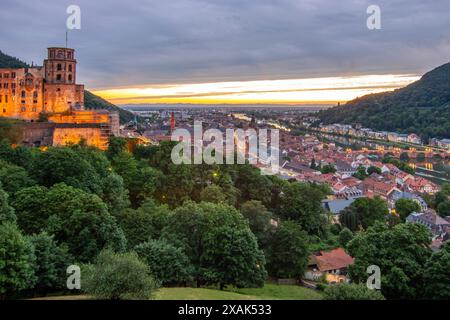 Blick auf eine Altstadt mit Burg oder Schlossruinen am Abend bei Sonnenuntergang. Diese Stadt liegt in einem Flusstal des Neckars, umgeben von Hügeln. Heidelberg, Baden-Württemberg, Deutschland Stockfoto