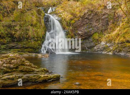 Klares orangefarbenes Wasser eines irischen Wasserfalls, der einen Hügel hinunterstürzt Stockfoto