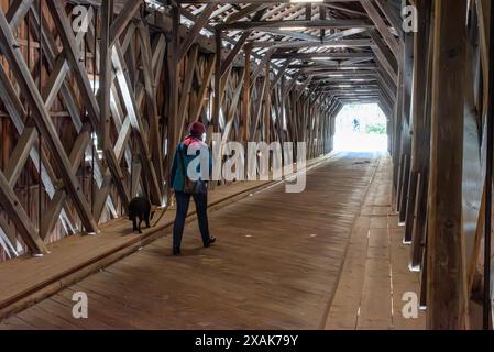 Ein Tourist, der die Grenze von Liechtenstein in die Schweiz an der historischen alten Rheinbrücke überquert Stockfoto