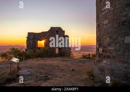 Mauern der Burgruine Desenberg in der Warburger Börde scheint die aufgehende Sonne durch die Öffnung in der Mauer und bildet einen Sonnenstern. Warburg, Landkreis Höxter, Nordrhein-Westfalen, Deutschland Stockfoto