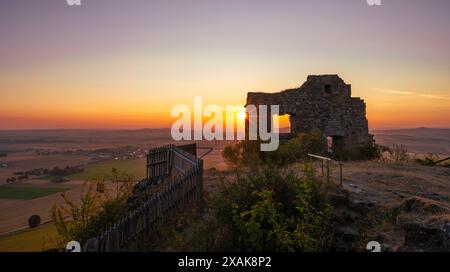 Mauern der Burgruine Desenberg in der Warburger Börde scheint die aufgehende Sonne durch die Öffnung in der Mauer und bildet einen Sonnenstern. Warburg, Landkreis Höxter, Nordrhein-Westfalen, Deutschland Stockfoto