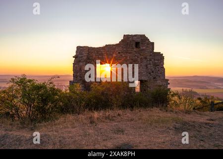 Mauern der Burgruine Desenberg in der Warburger Börde scheint die aufgehende Sonne durch die Öffnung in der Mauer und bildet einen Sonnenstern. Warburg, Landkreis Höxter, Nordrhein-Westfalen, Deutschland Stockfoto