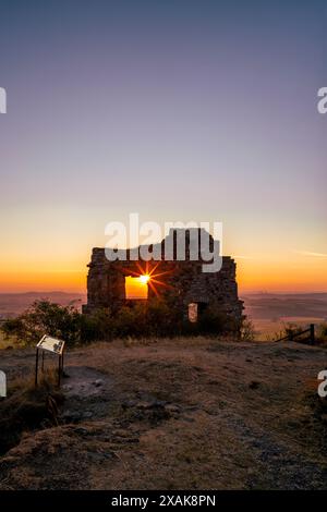 Mauern der Burgruine Desenberg in der Warburger Börde scheint die aufgehende Sonne durch die Öffnung in der Mauer und bildet einen Sonnenstern. Warburg, Landkreis Höxter, Nordrhein-Westfalen, Deutschland Stockfoto