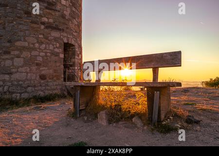 Donjon der Burgruine Desenberg in der Warburg Börde bei Sonnenaufgang im Sommer, eine Bank im Vordergrund. Warburg, Landkreis Höxter, Nordrhein-Westfalen, Deutschland Stockfoto